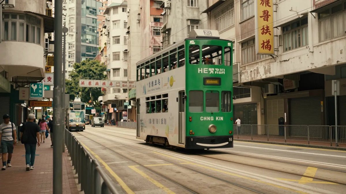 A green and cream Hong Kong double-decker tram turning onto Central tram tracks, framed by colonial-era shophouses with Cantonese signage