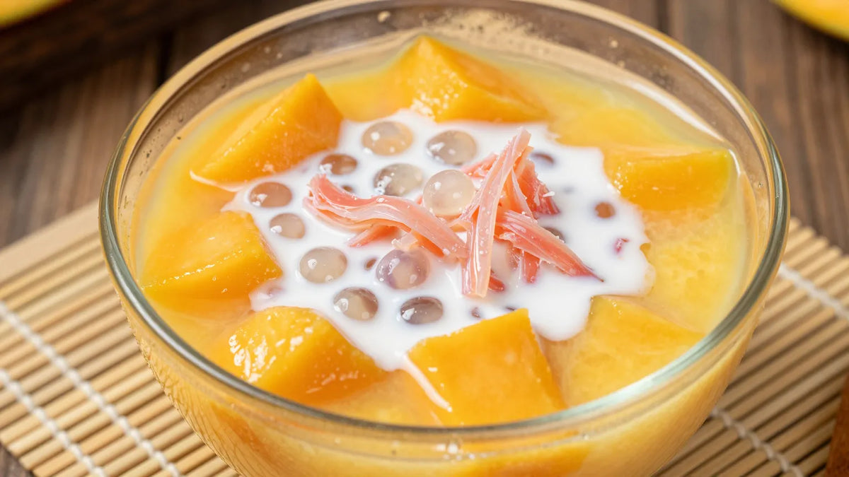 Overhead view of a glass bowl of Cantonese mango pomelo sago dessert with mango puree, sago pearls, pomelo pulp and coconut milk