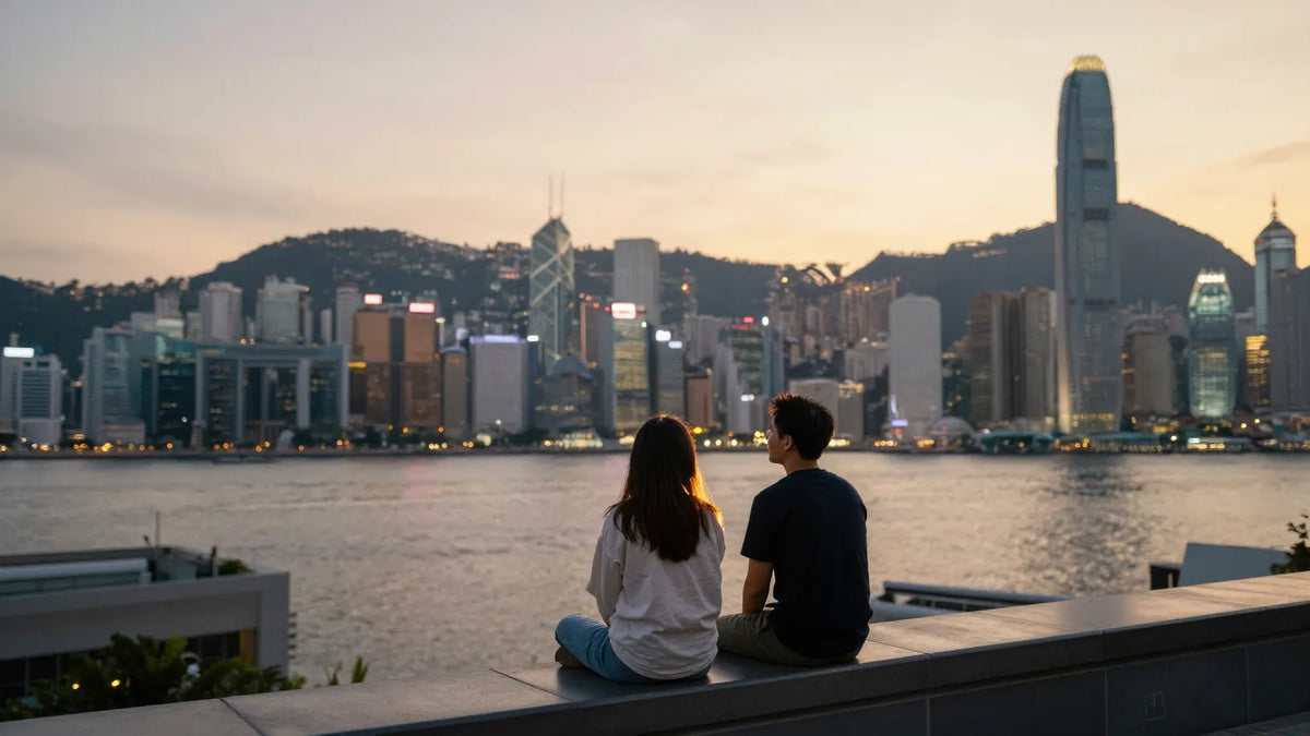 Young Hong Kong couple sitting on a rooftop at sunset looking at the harbor skyline