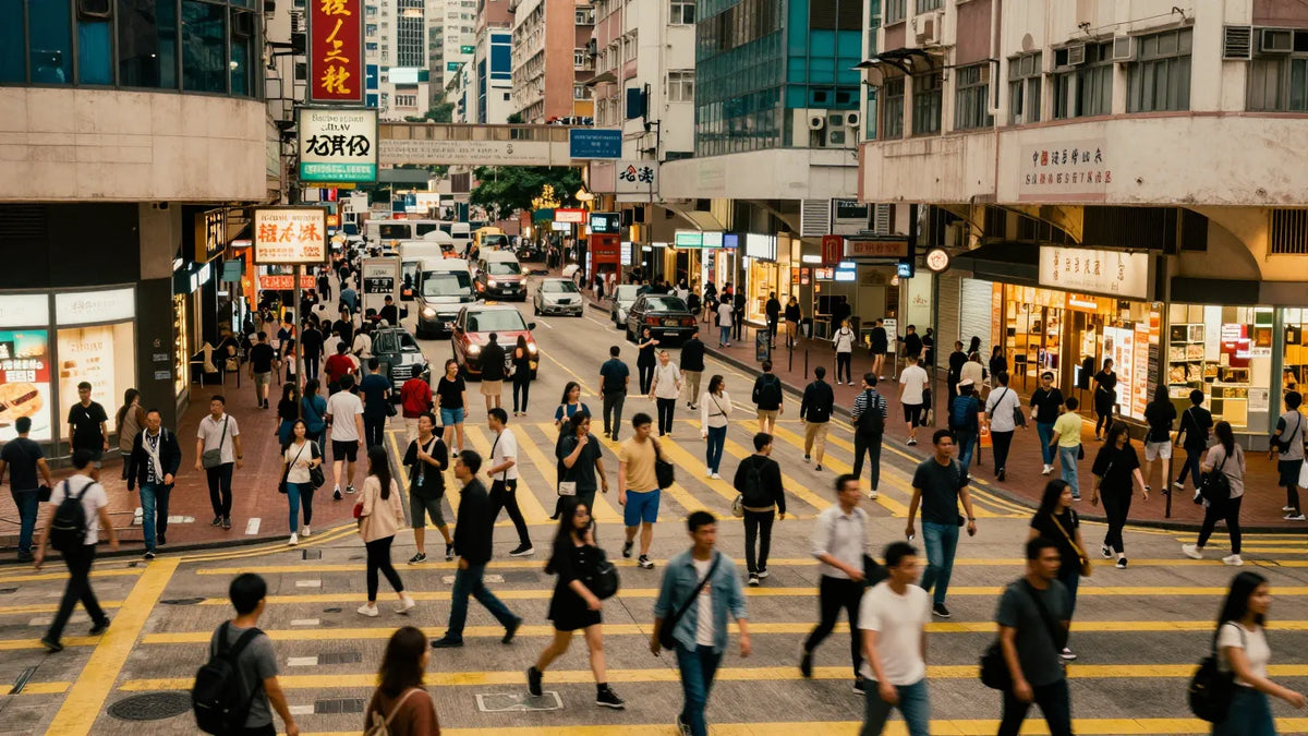Overhead wide shot of a busy Causeway Bay pedestrian crossing at dusk with crowds moving between blocks of neon signs and shops