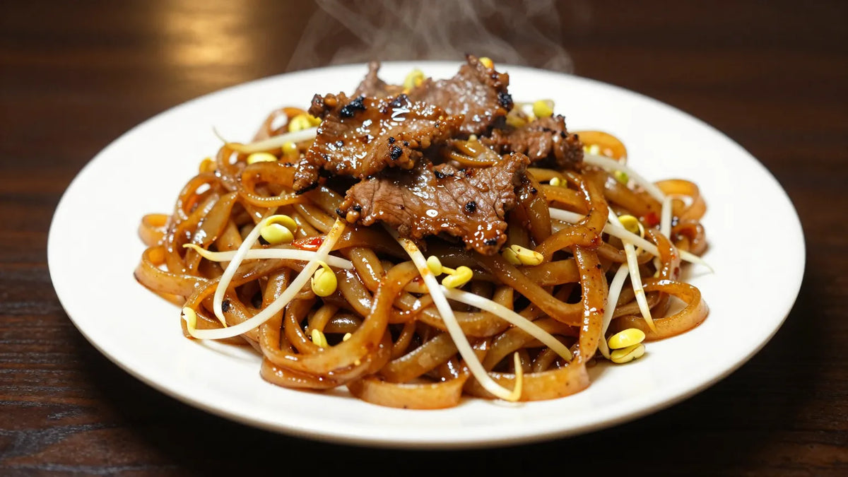 Steaming dry-fried beef chow fun with charred beef slices, flat rice noodles and bean sprouts on a white plate