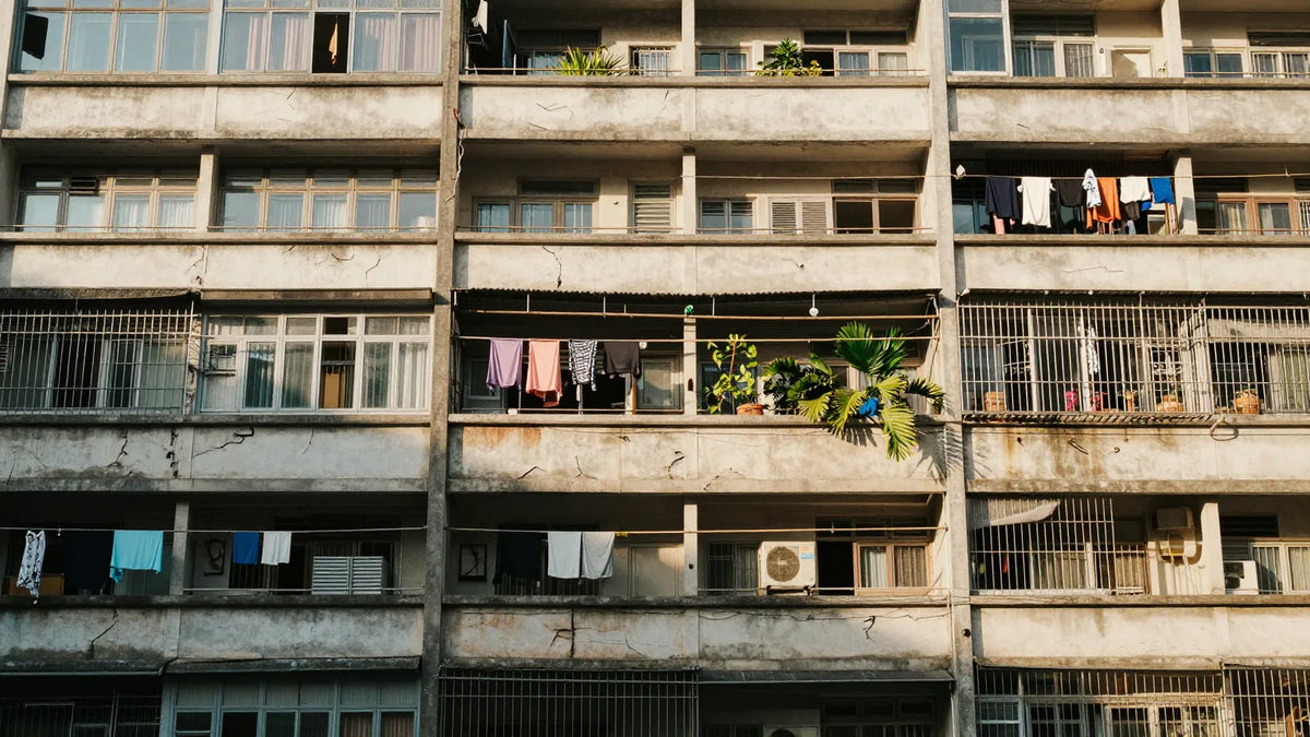 Weathered concrete facade of a 1950s Hong Kong public housing resettlement block with hanging laundry on balconies