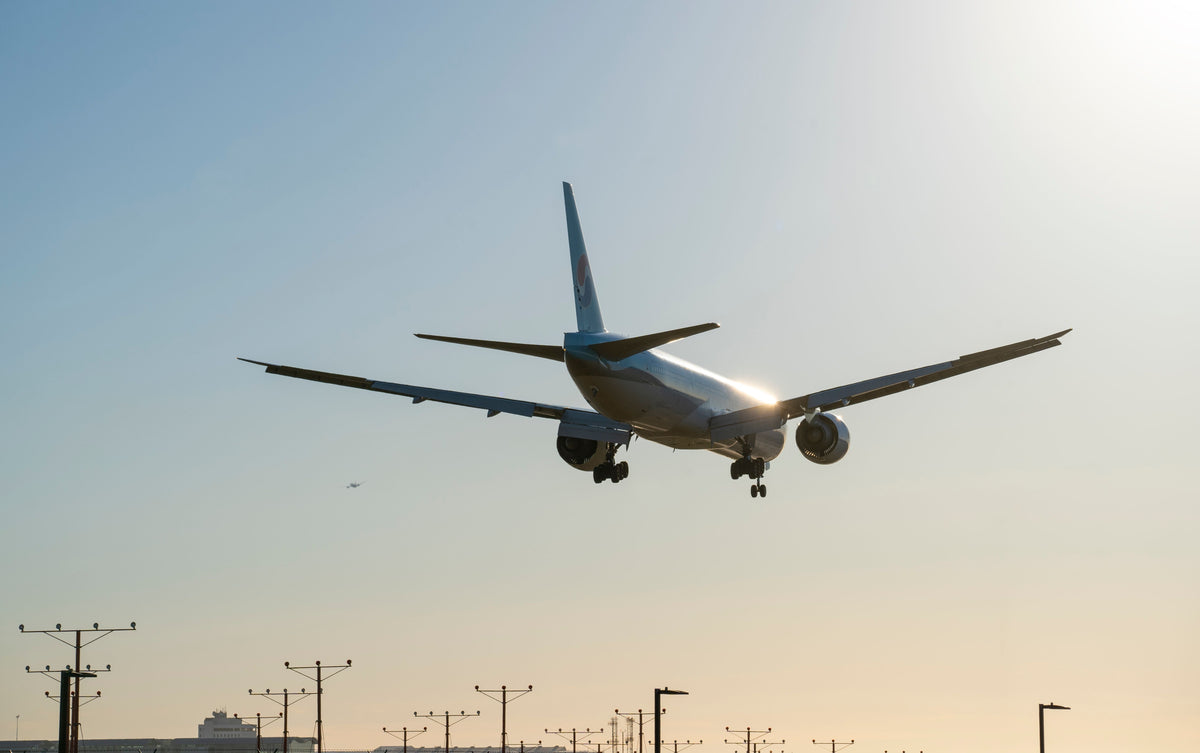 A commercial airplane landing at sunset — an echo of Kai Tak's legendary approach through Kowloon