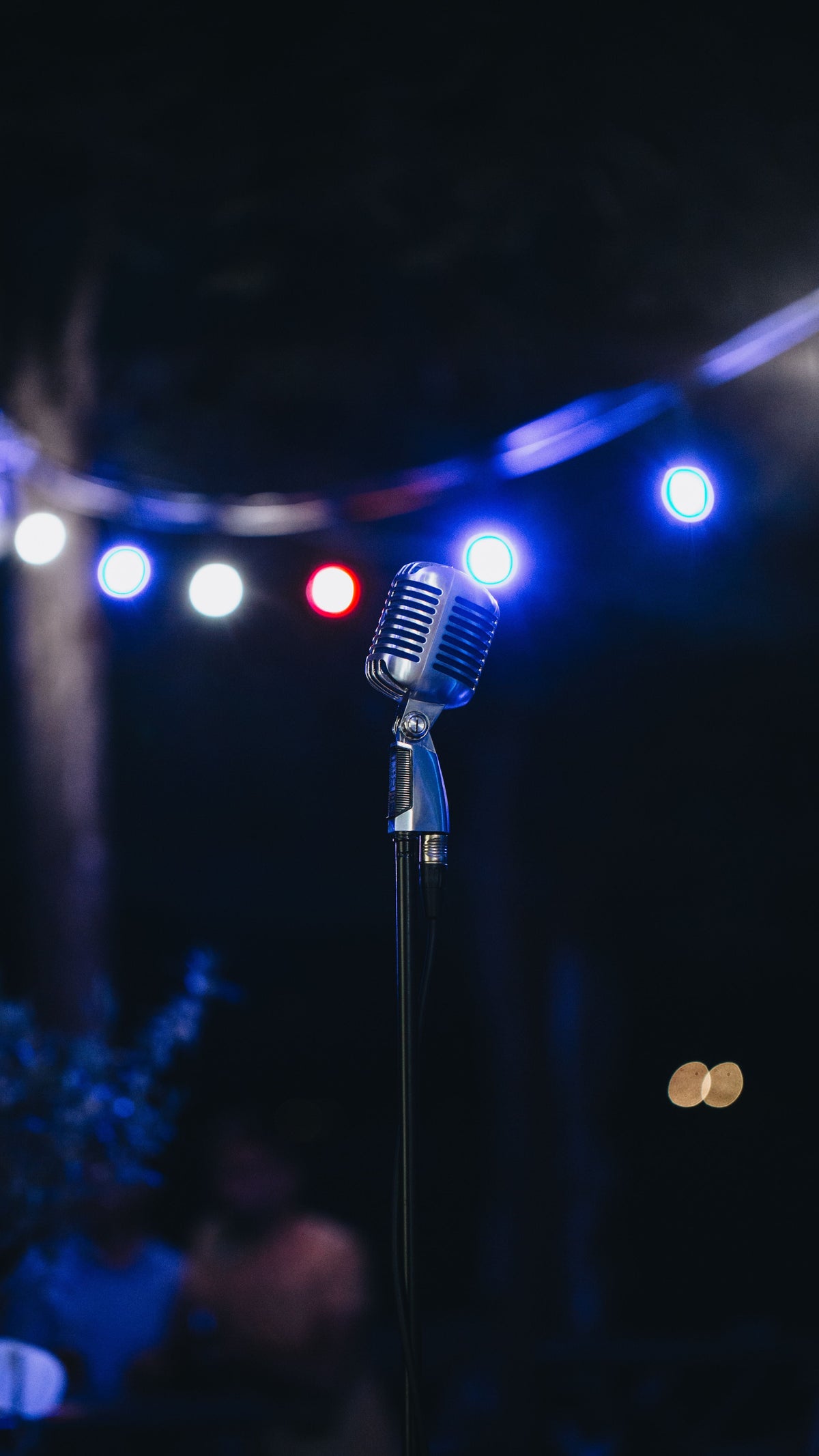 Microphone on a concert stage under warm spotlights — the era imagery of 1990s Cantopop