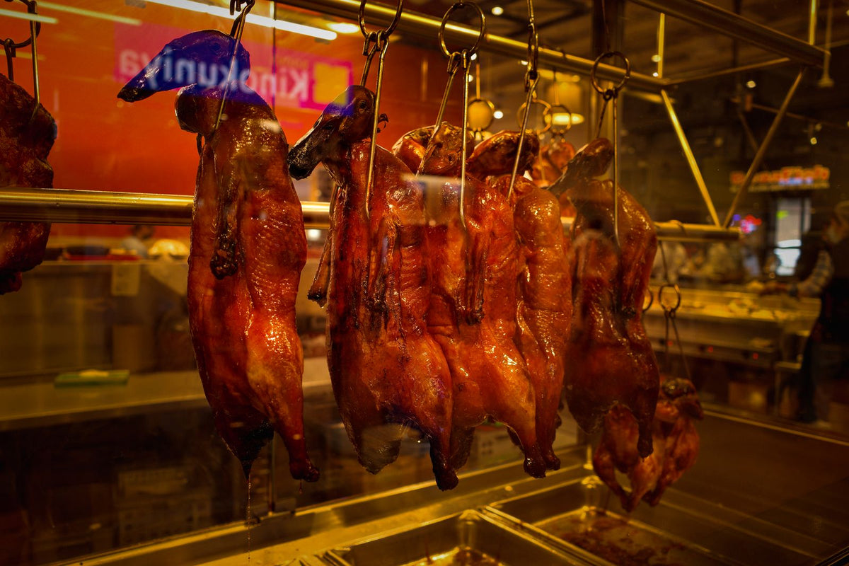Roasted birds hanging in a Chinese butcher window with lacquered bronze skin