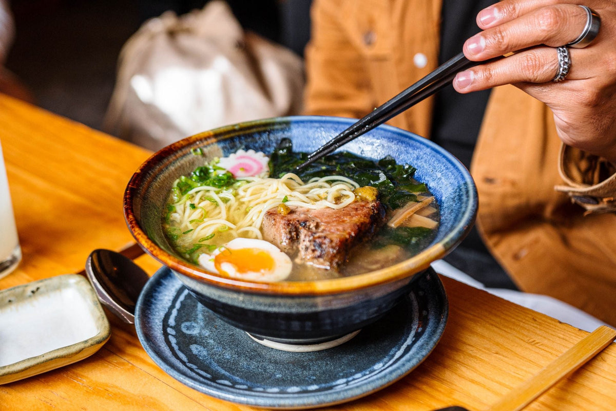 Close-up of a small bowl of hot Asian noodle soup with chopsticks and delicate broth