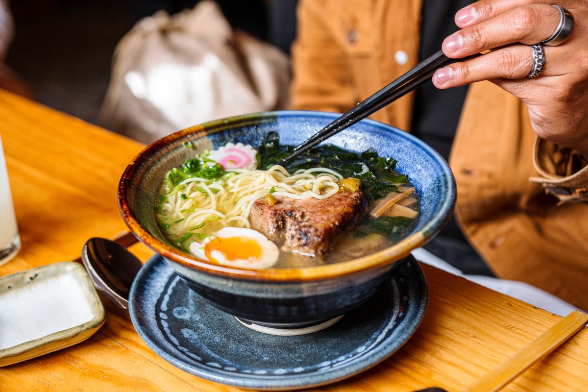 A vibrant bowl of Asian broth with chopsticks resting on the rim
