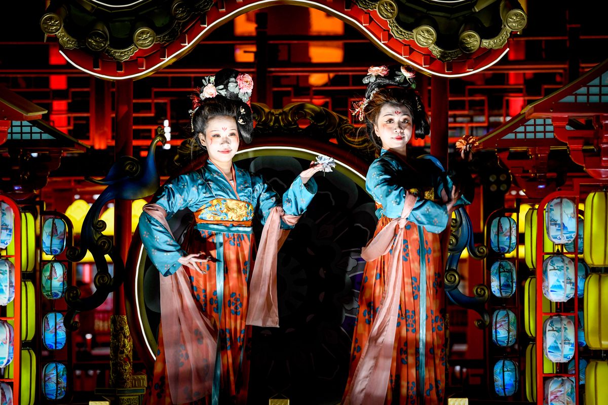 Performers in traditional Chinese opera costumes under vibrant lights