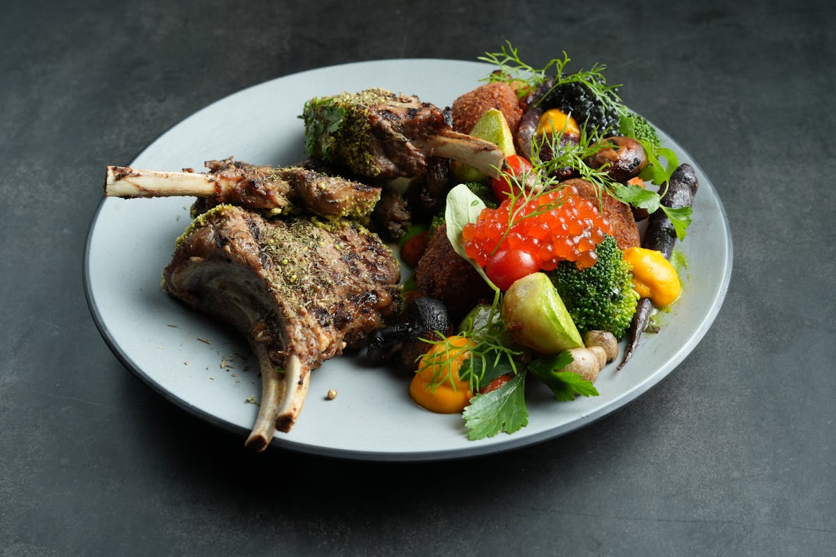 Roasted meat with colorful vegetables on a white plate
