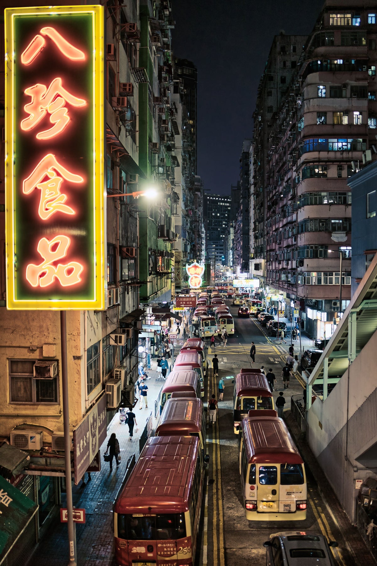 A bustling Hong Kong street at night with layered neon signs and traffic