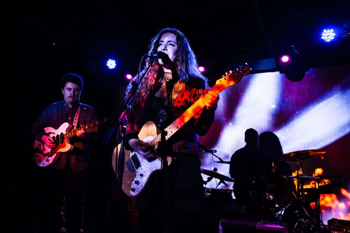 Musical band performing on stage with purple and white stage lights, capturing the energy of Cantopop performances
