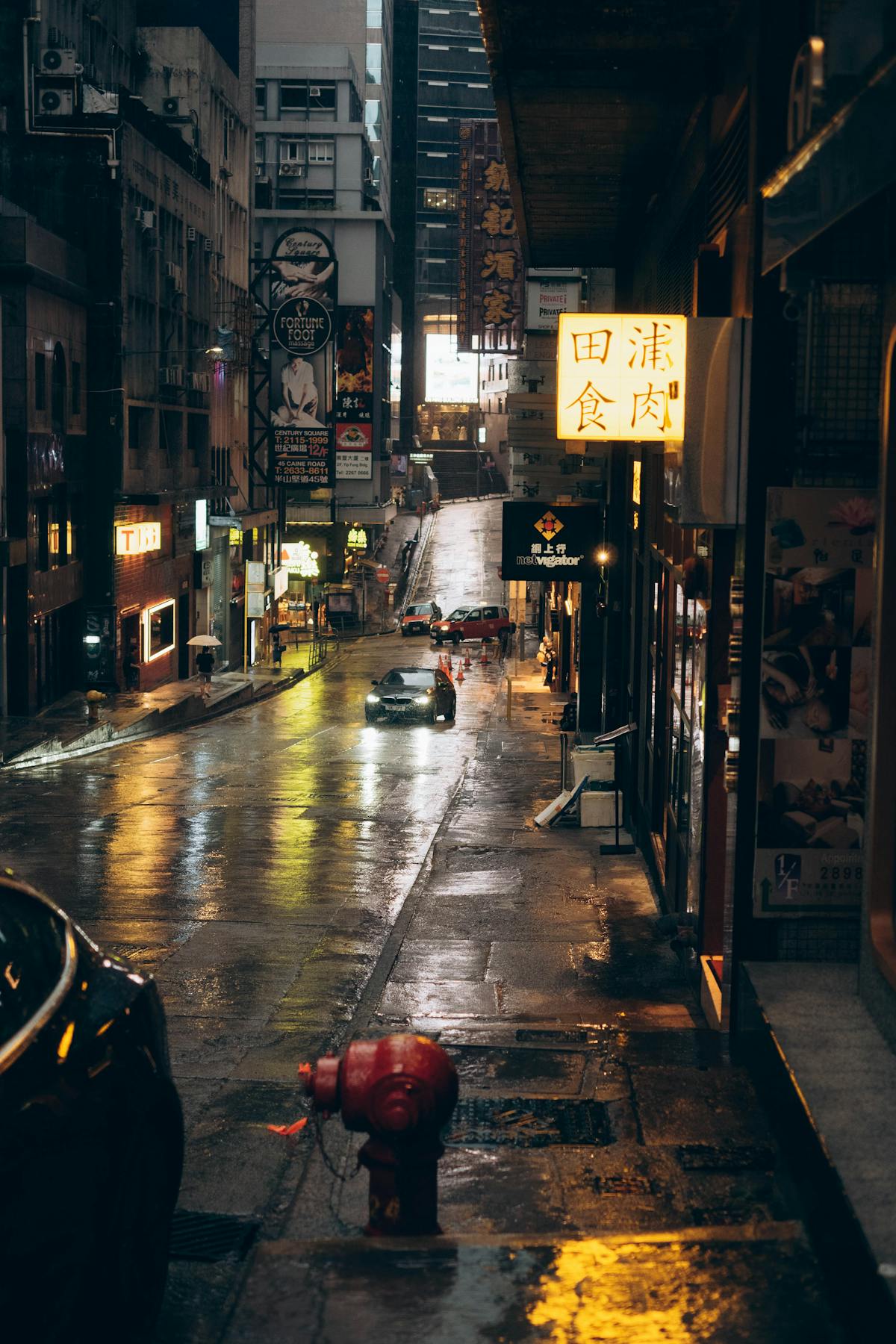 Rain-soaked Hong Kong street at night with neon lights reflecting on wet pavement