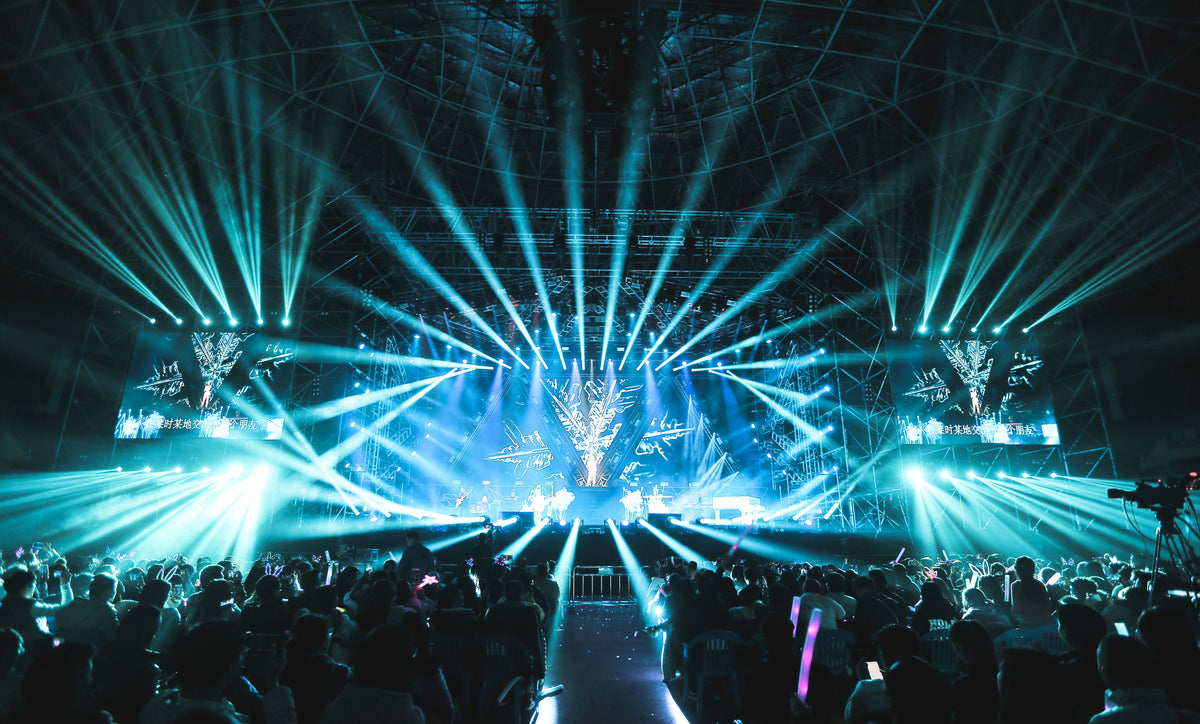 Concert stage lights cutting through darkness and haze representing Cantopop performance