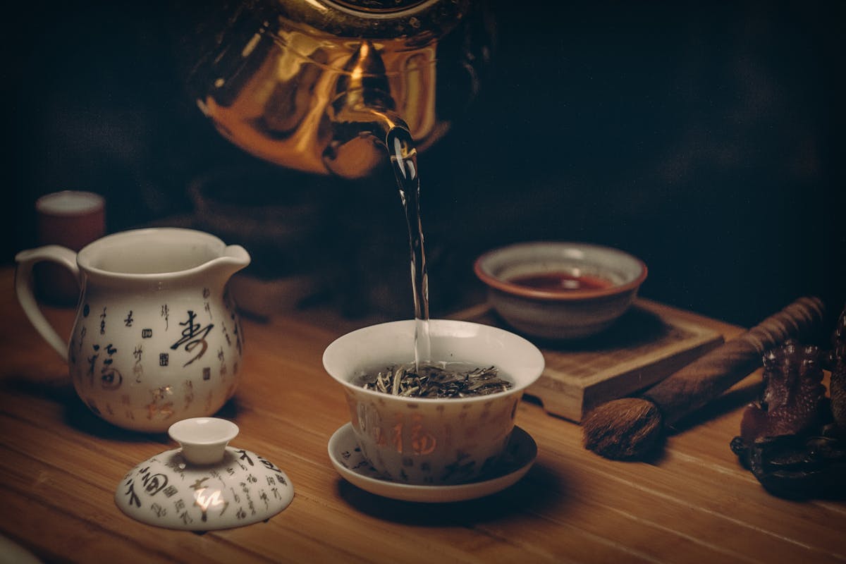 Gold kettle pouring hot water into a cup of tea