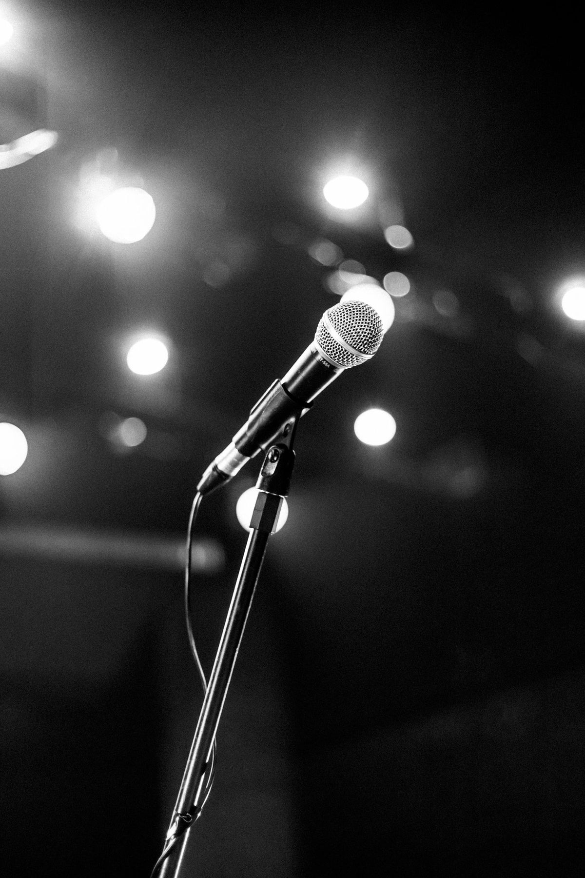 Empty concert stage with microphone under a single spotlight, evoking a farewell concert atmosphere