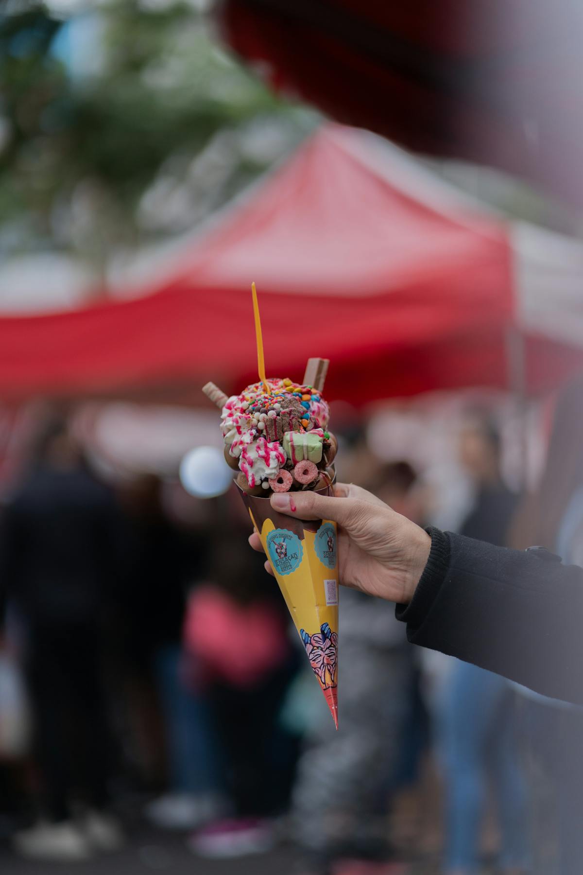 Hand holding a Hong Kong-style egg waffle (bubble waffle) with ice cream and toppings