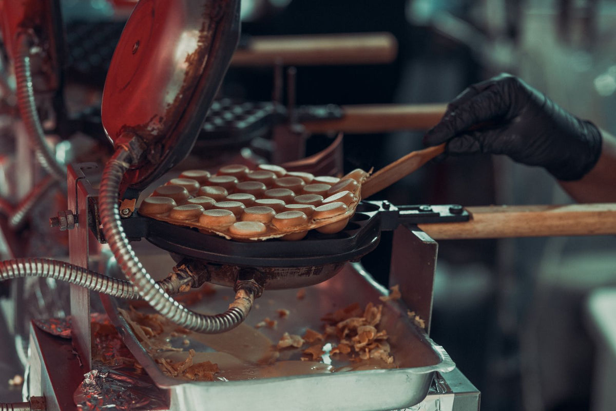 Close-up of Hong Kong style bubble egg waffles cooking in a professional waffle maker at a street market