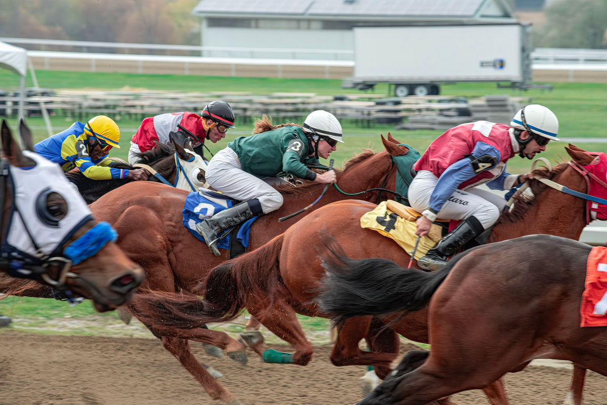 Horses and jockeys racing at speed down a floodlit track with an intense colorful atmosphere