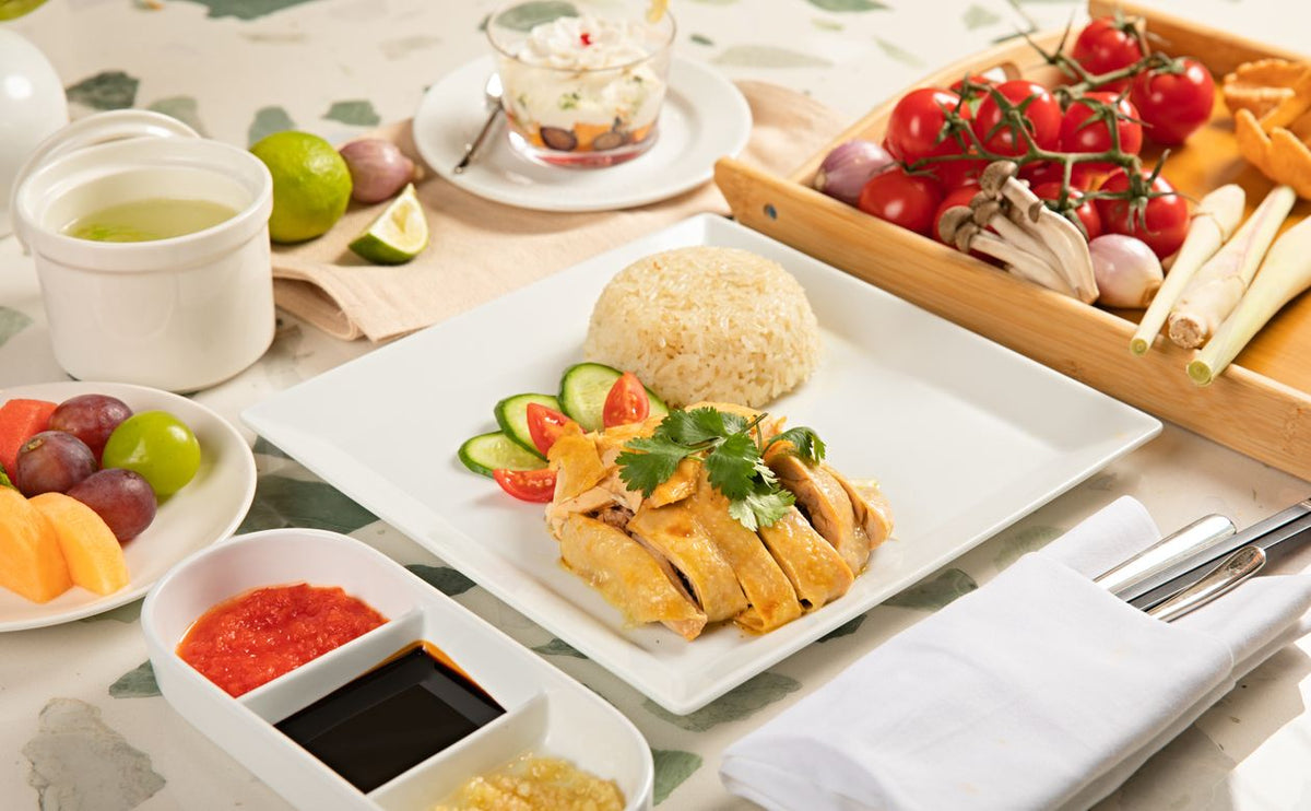 Hainanese chicken rice dish plated with fresh garnish, cucumber slices and sides in Cantonese style