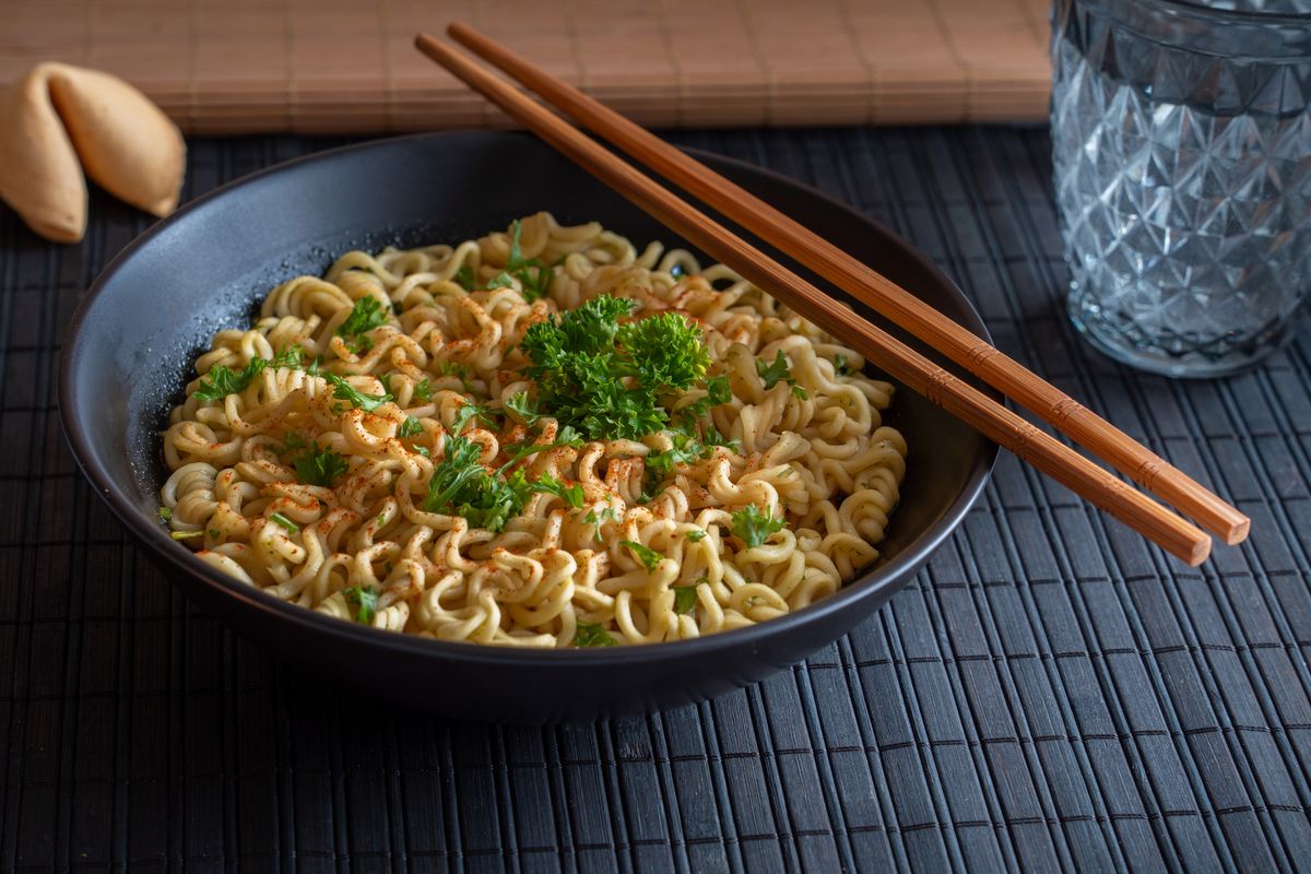 A bowl of noodle soup garnished with fresh herbs and spring onions