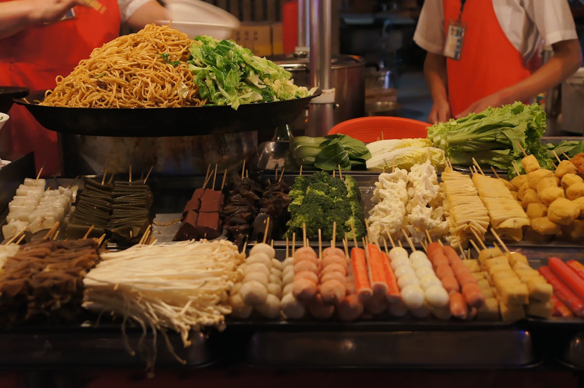 Vibrant Asian street food vendor display with assorted skewers and meats