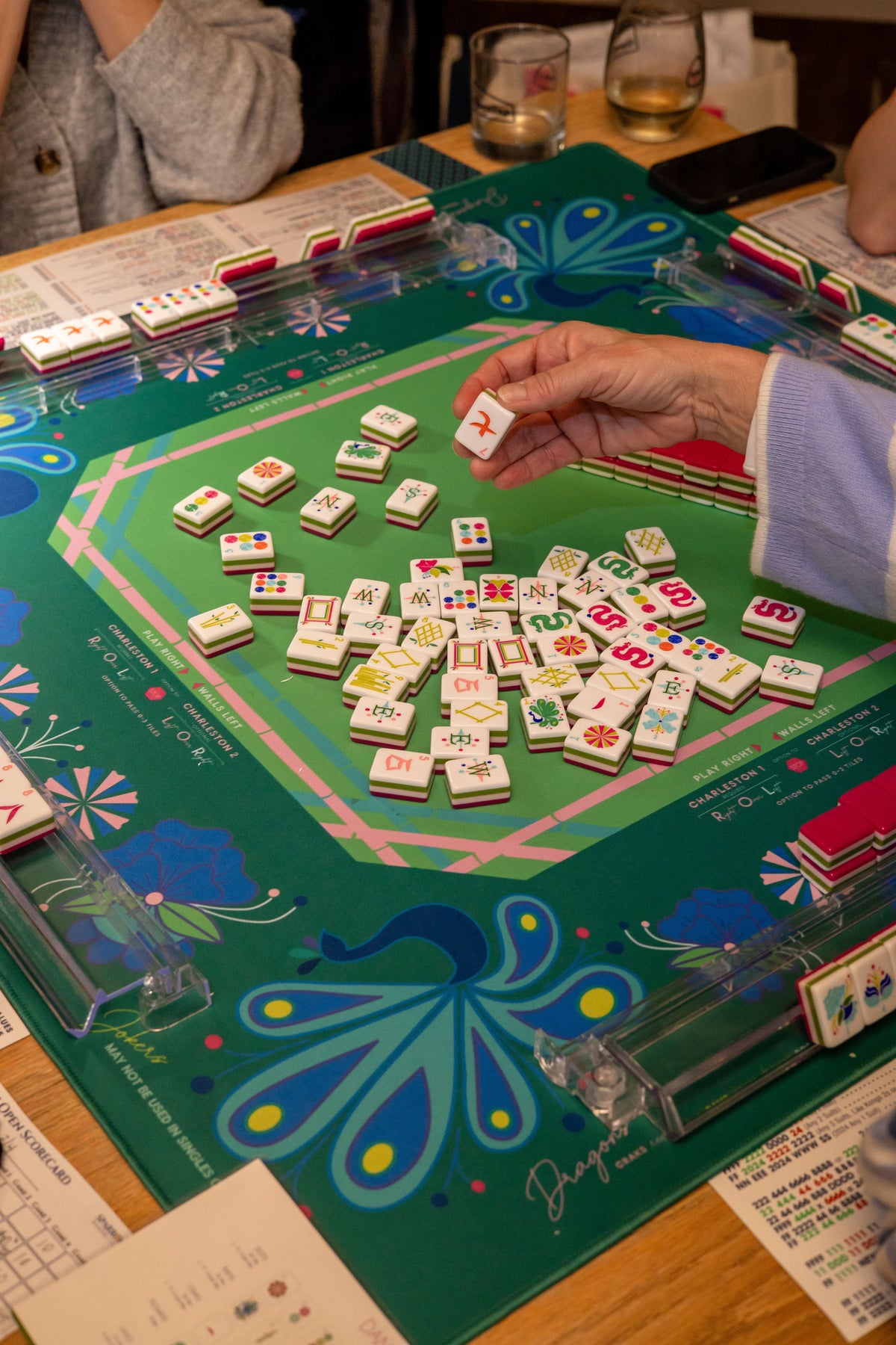 A mahjong game night set up on a decorative table with tiles laid out ready to play