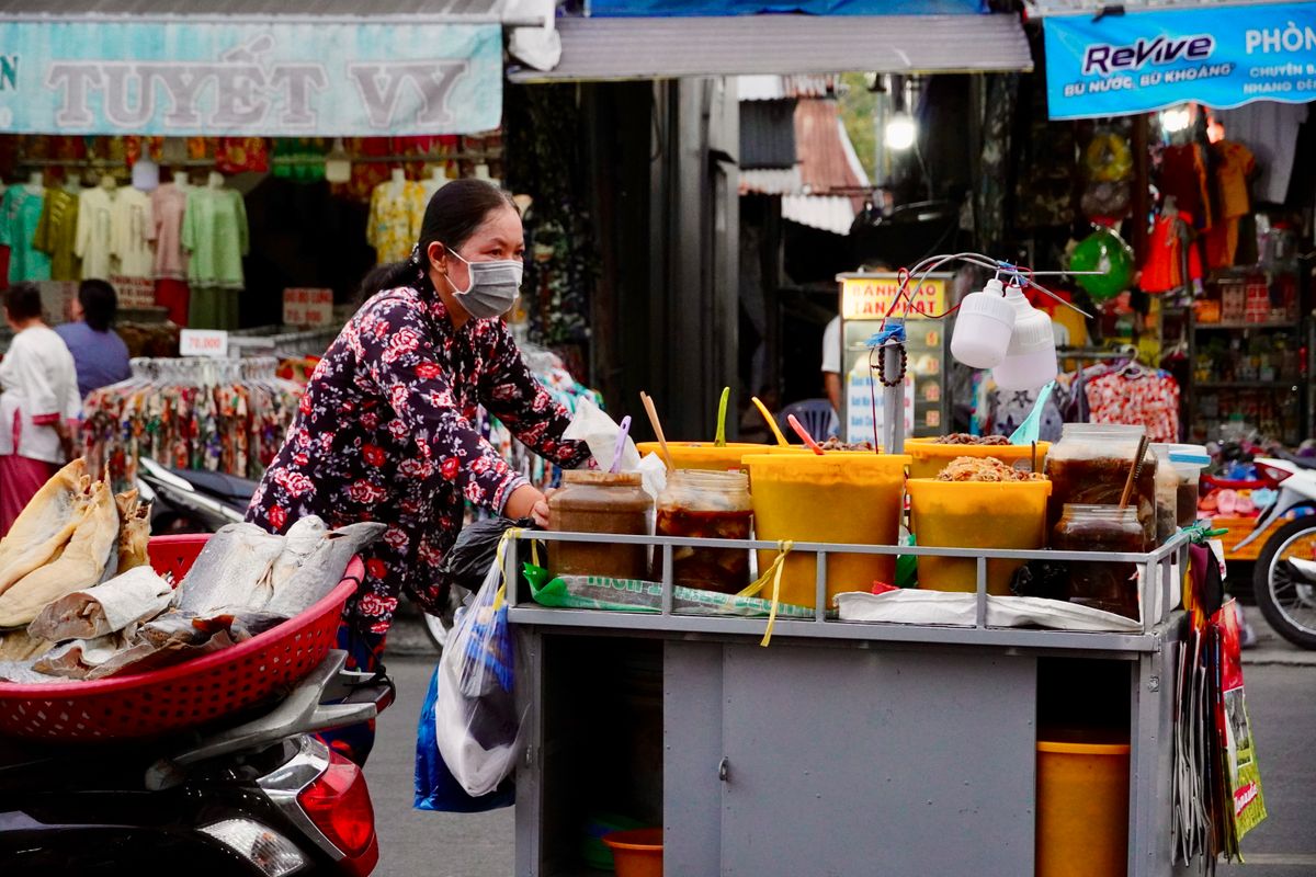 A street vendor pushes a colourful food cart through a bustling market