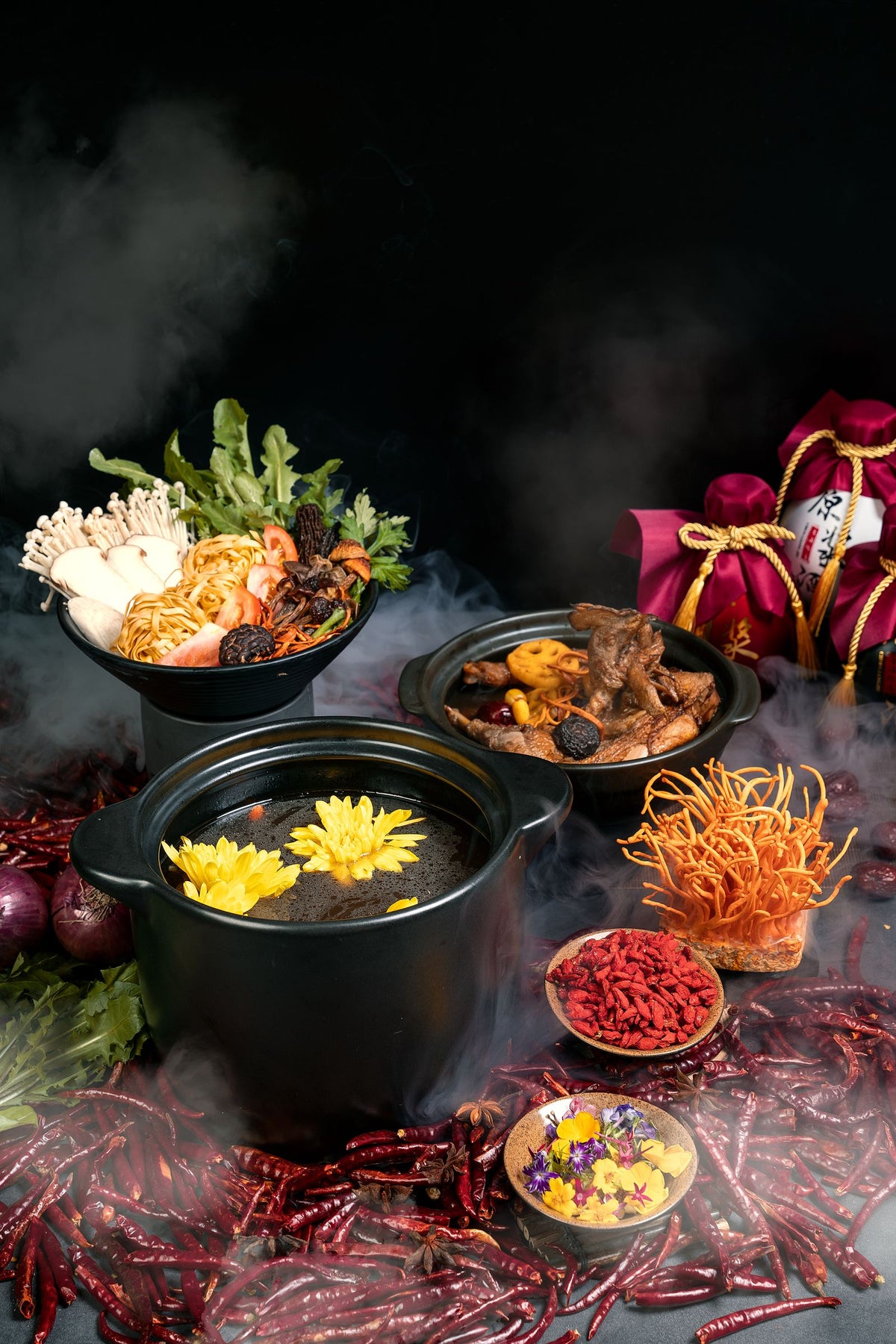 Vibrant Chinese hot pot with herbs, spices, and ingredients, shown with rising steam