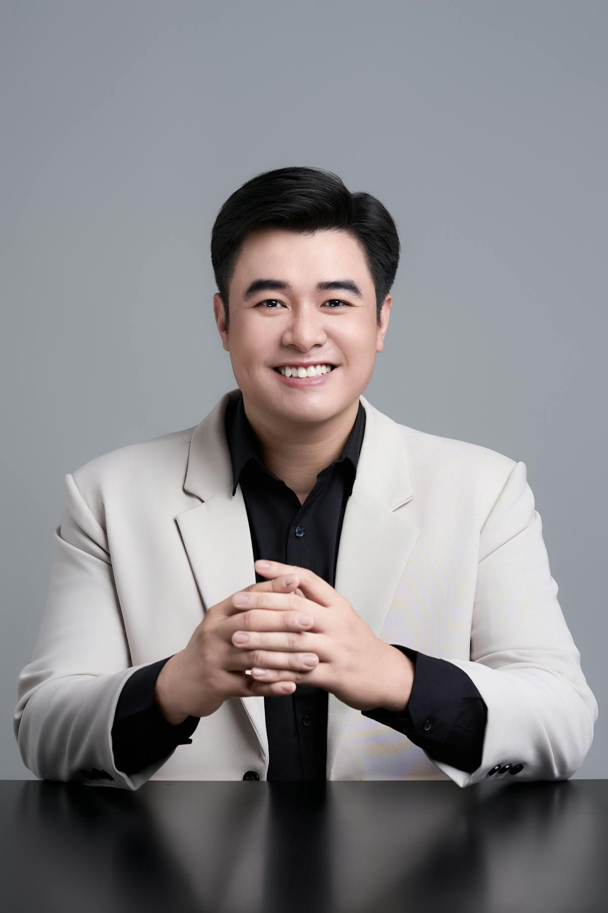 Professional portrait of an Asian man smiling confidently in a studio