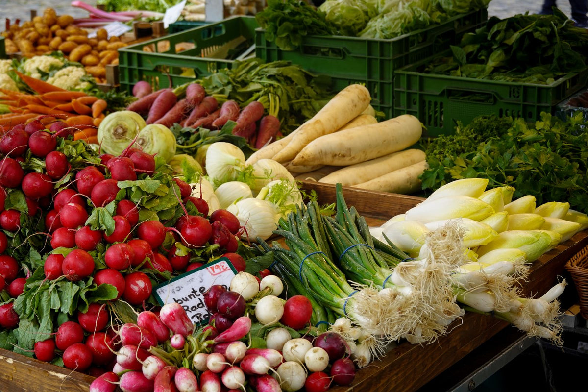 Vibrant market vegetable display with produce stacked at a stall