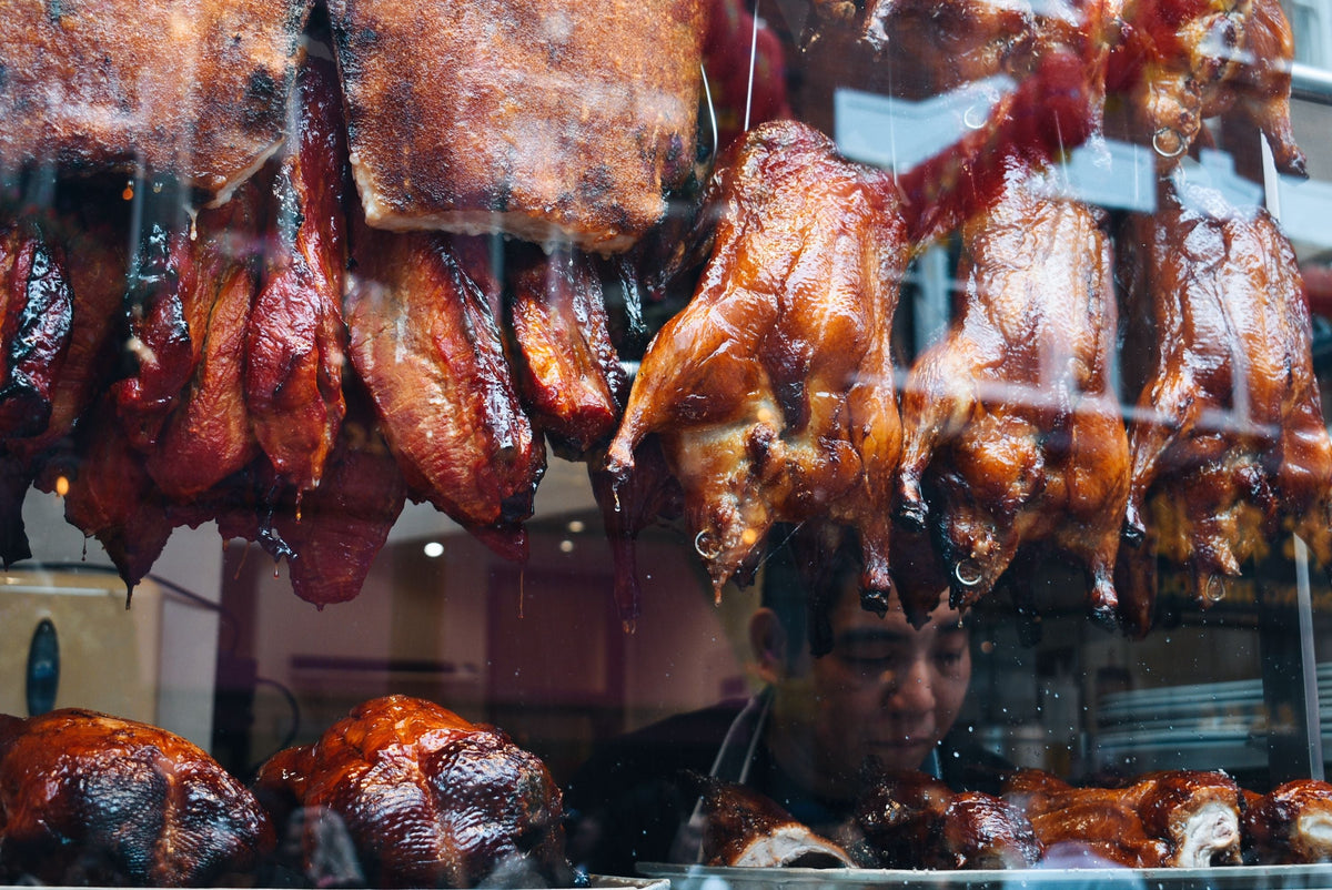 Cantonese roast meats including roast duck and pork hanging in a traditional Chinese deli window