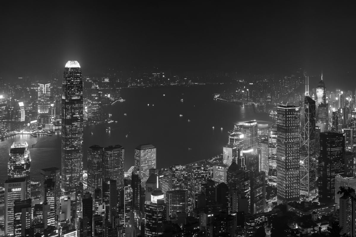 Black and white photograph of the Hong Kong skyline lit up at night