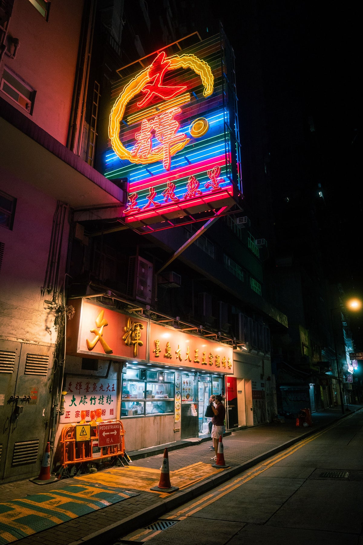 Hong Kong street at night with colorful neon signs glowing above the road
