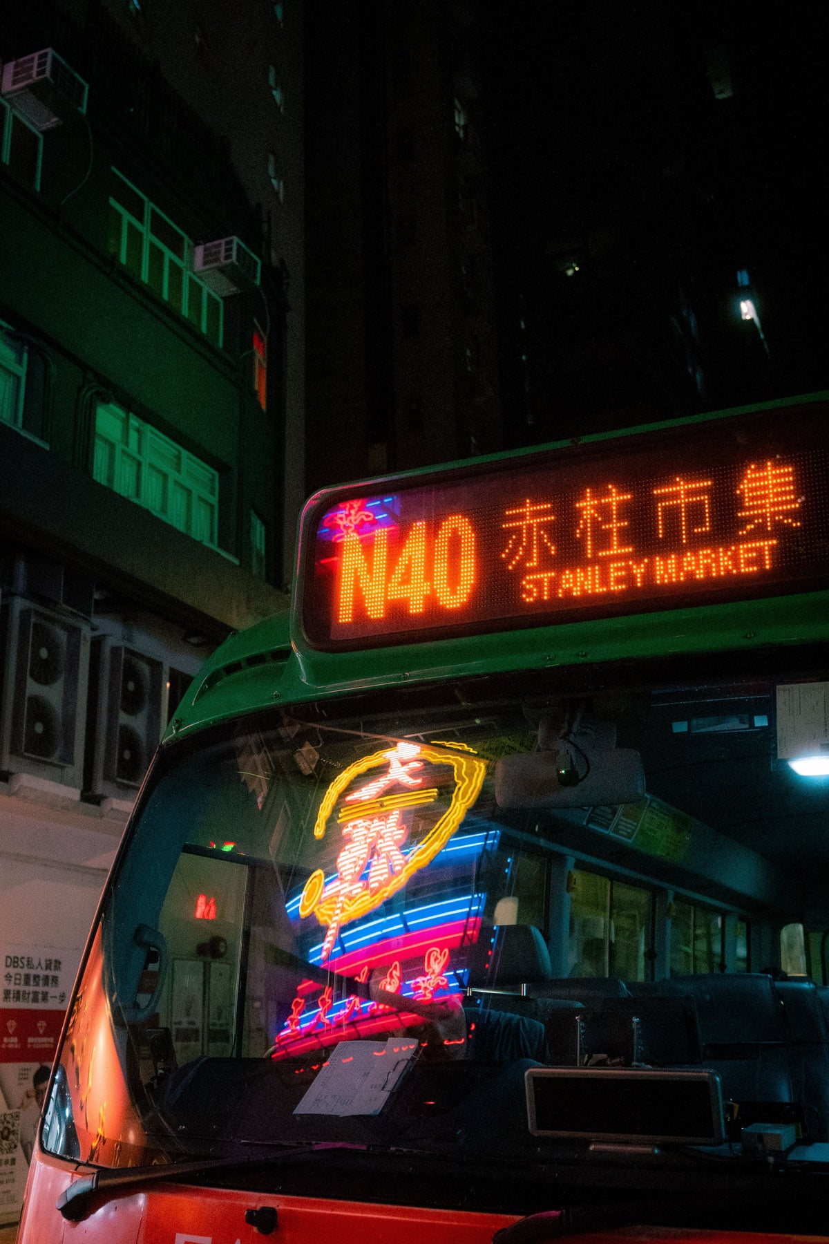 Hong Kong public bus at night with neon signs and city traffic along the route