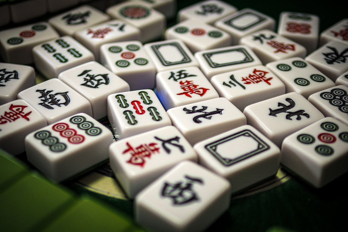Mahjong tiles arranged on green felt with Chinese character suits visible
