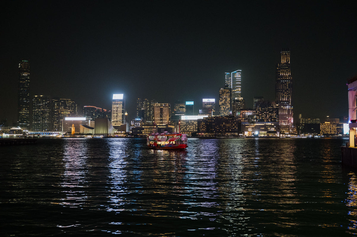 Hong Kong skyline at night with ferries crossing Victoria Harbour