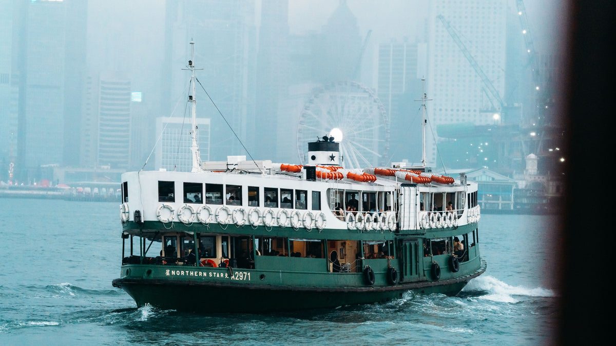 A classic Hong Kong ferry crosses foggy Victoria Harbour with the city skyline behind it