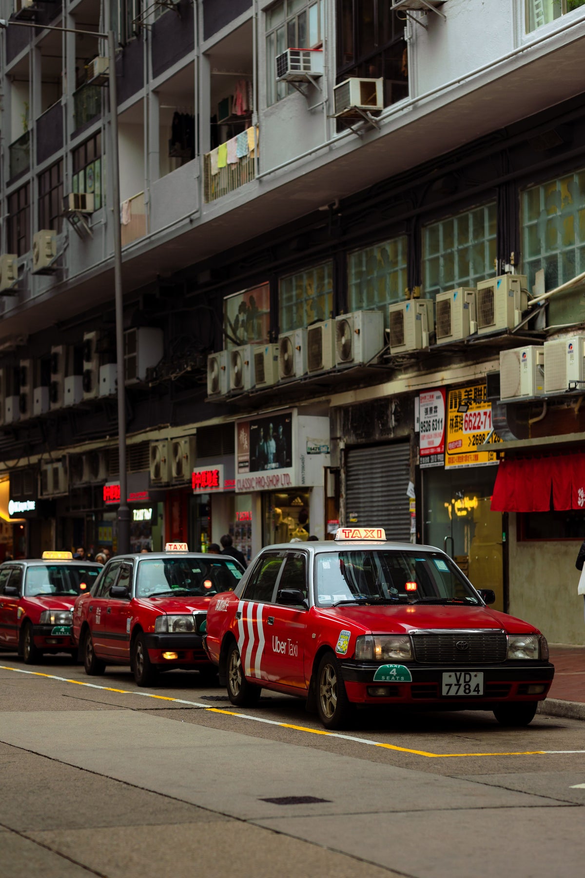 Row of red Hong Kong Toyota Crown Comfort taxis lined up on a city street
