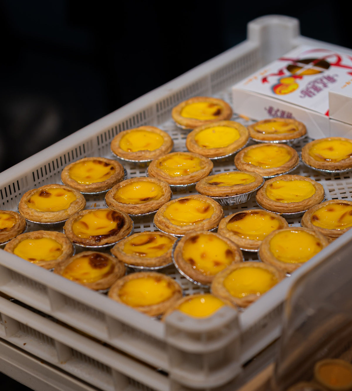 Freshly baked Hong Kong egg tarts arranged in a bakery tray