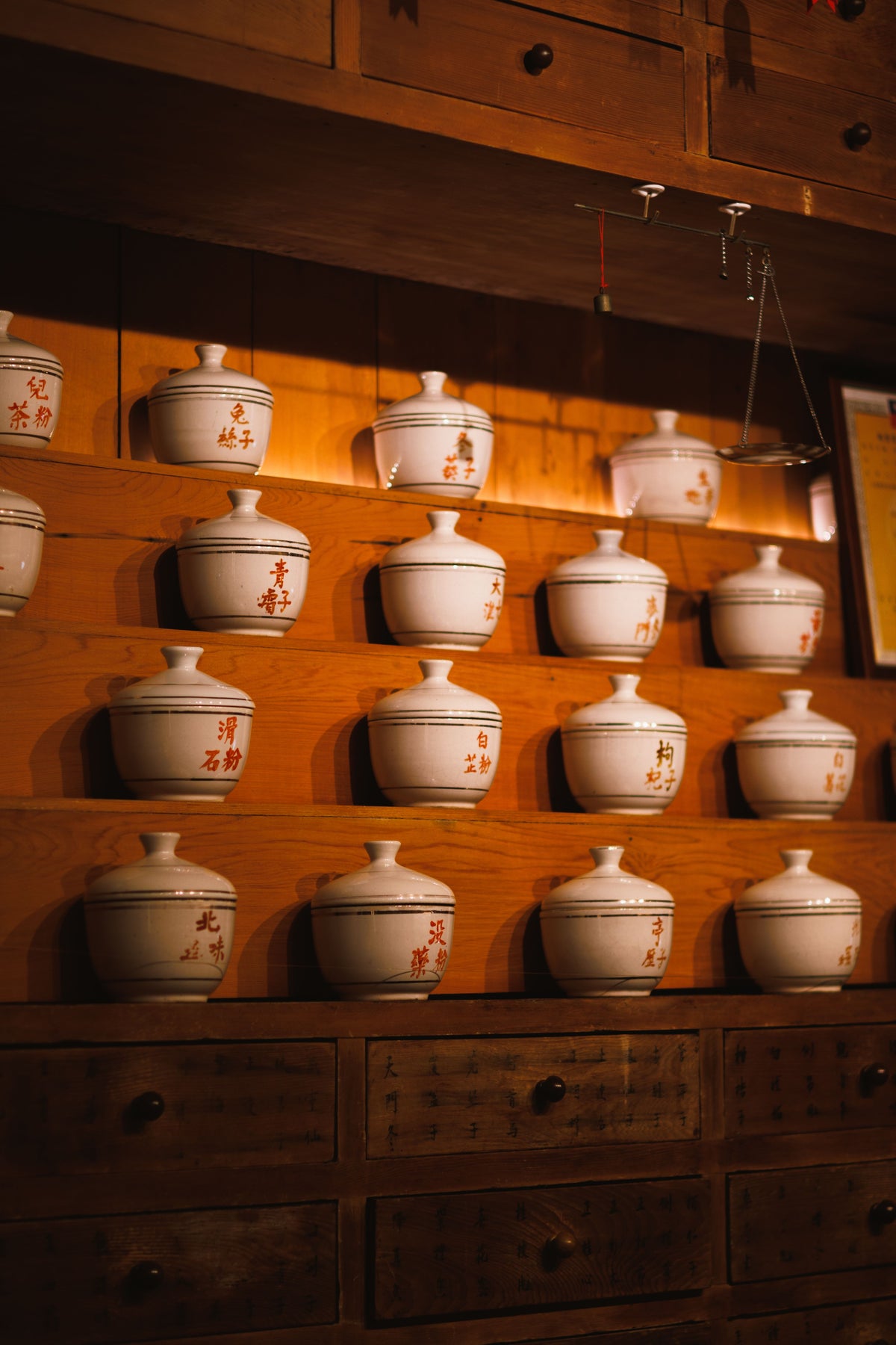 Rows of traditional apothecary jars with red script in a dimly lit Chinese herbal shop