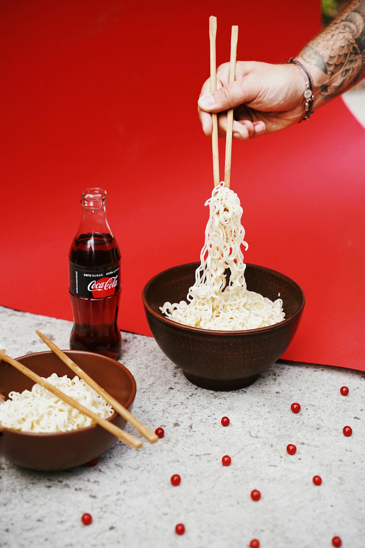 Person lifting springy noodles from a ceramic bowl with wooden chopsticks