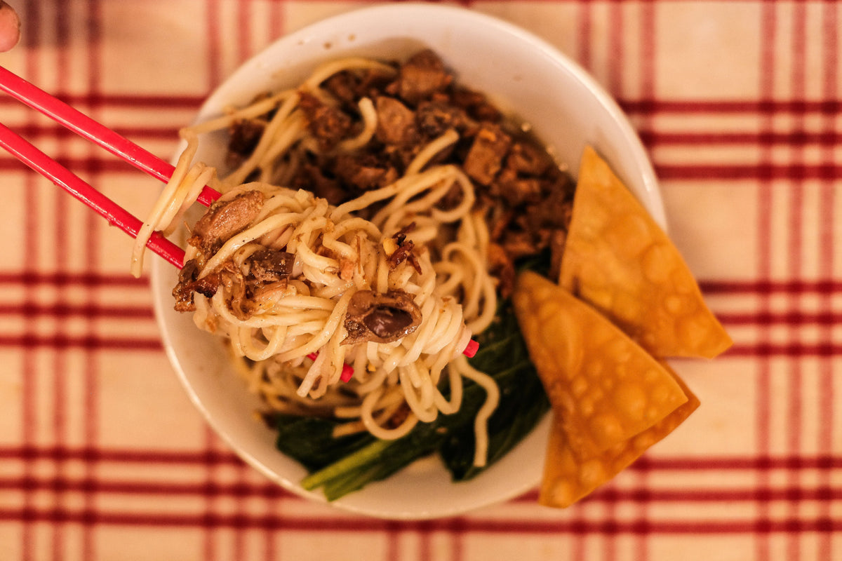 Asian noodle bowl with chopsticks representing Hong Kong wonton noodles