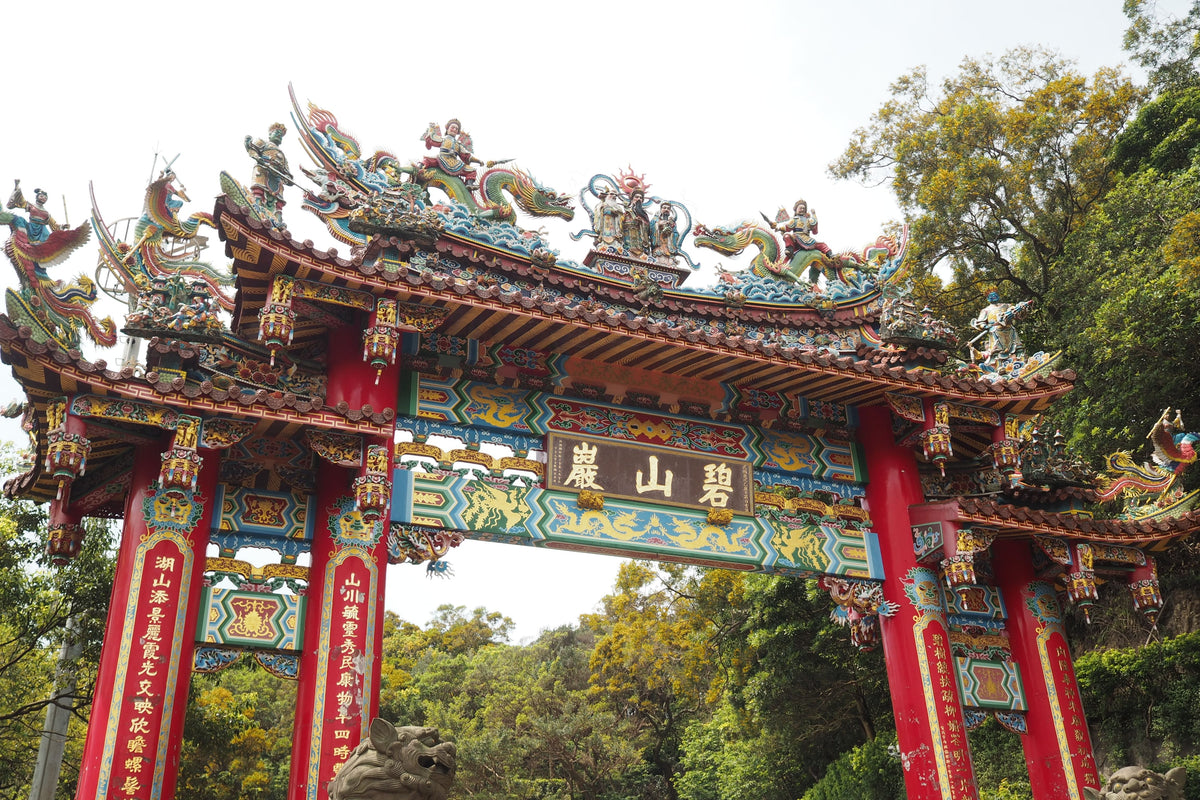 Vibrant ornate Chinese temple gate with intricate dragon sculptures — the architectural universe of Lam Ching-ying's jiangshi films