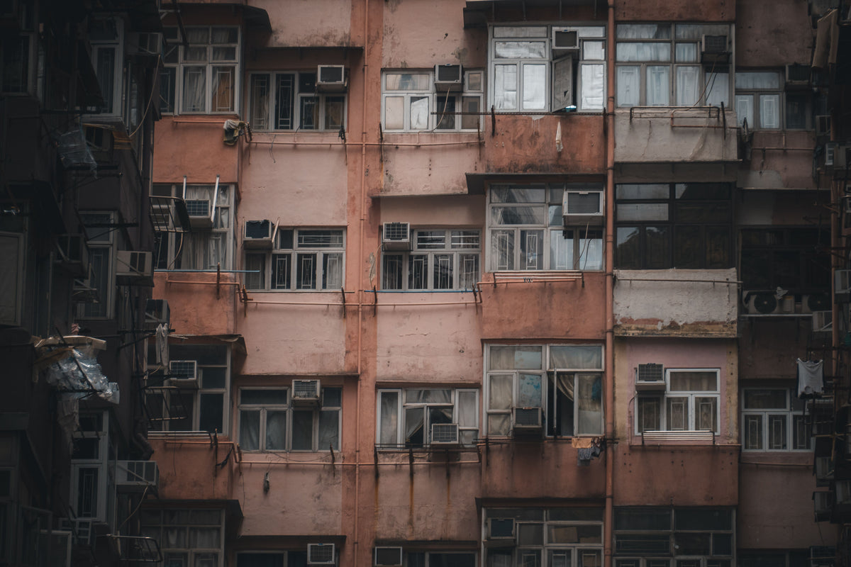 Aging Hong Kong residential tenement building facade with air conditioning units and weathered concrete