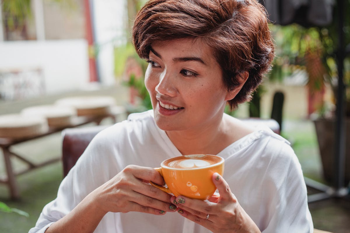 Smiling Asian woman drinking a cup of coffee