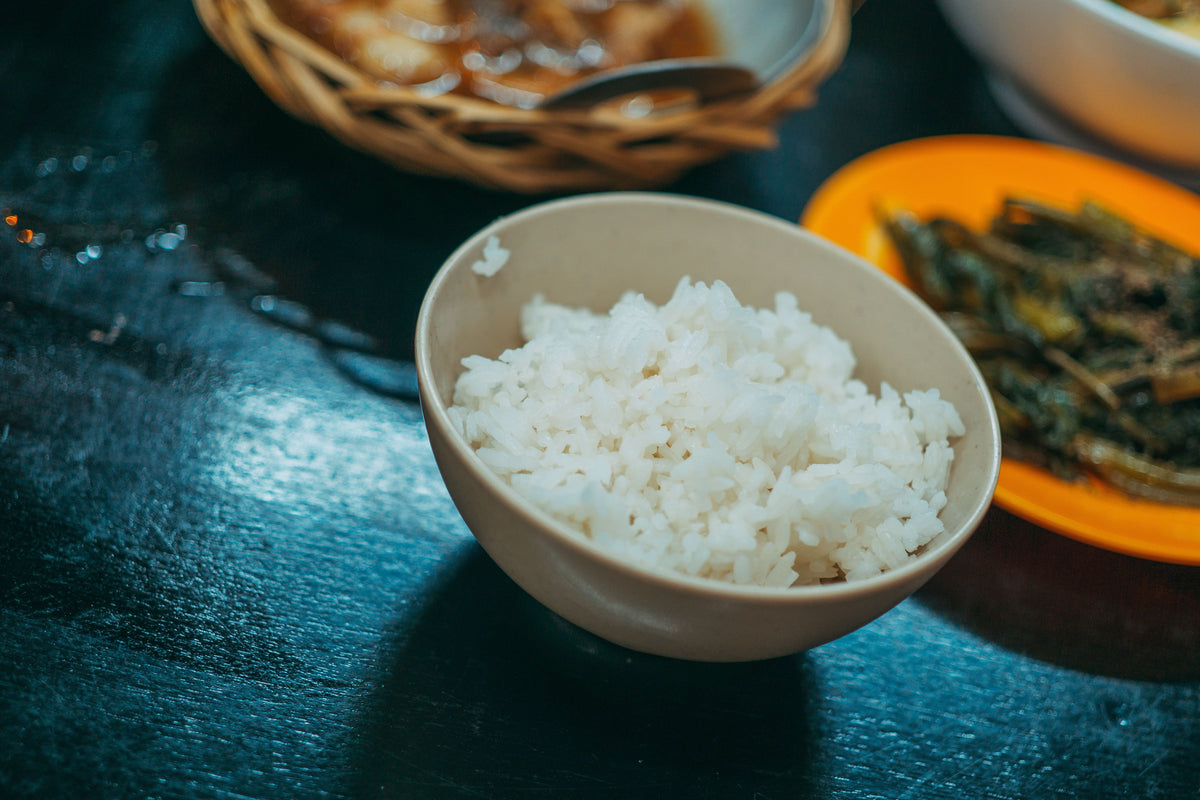 A close-up bowl of rice porridge with vegetables on the side