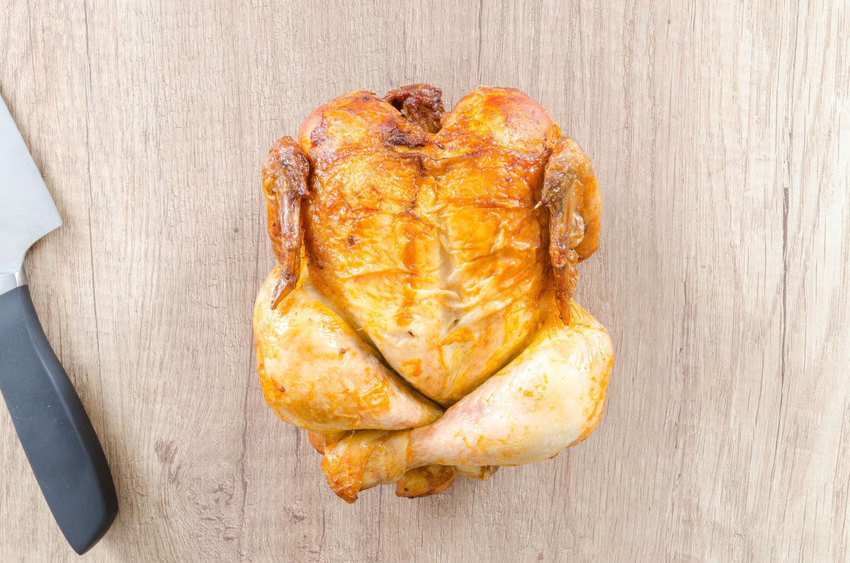 Golden crispy-skinned whole roasted chicken presented on a wooden serving board