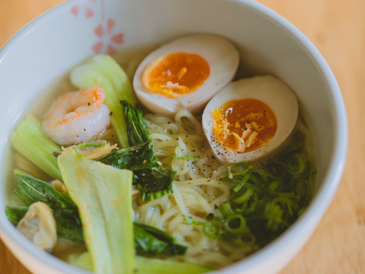 Bowl of noodle soup with boiled egg and golden broth