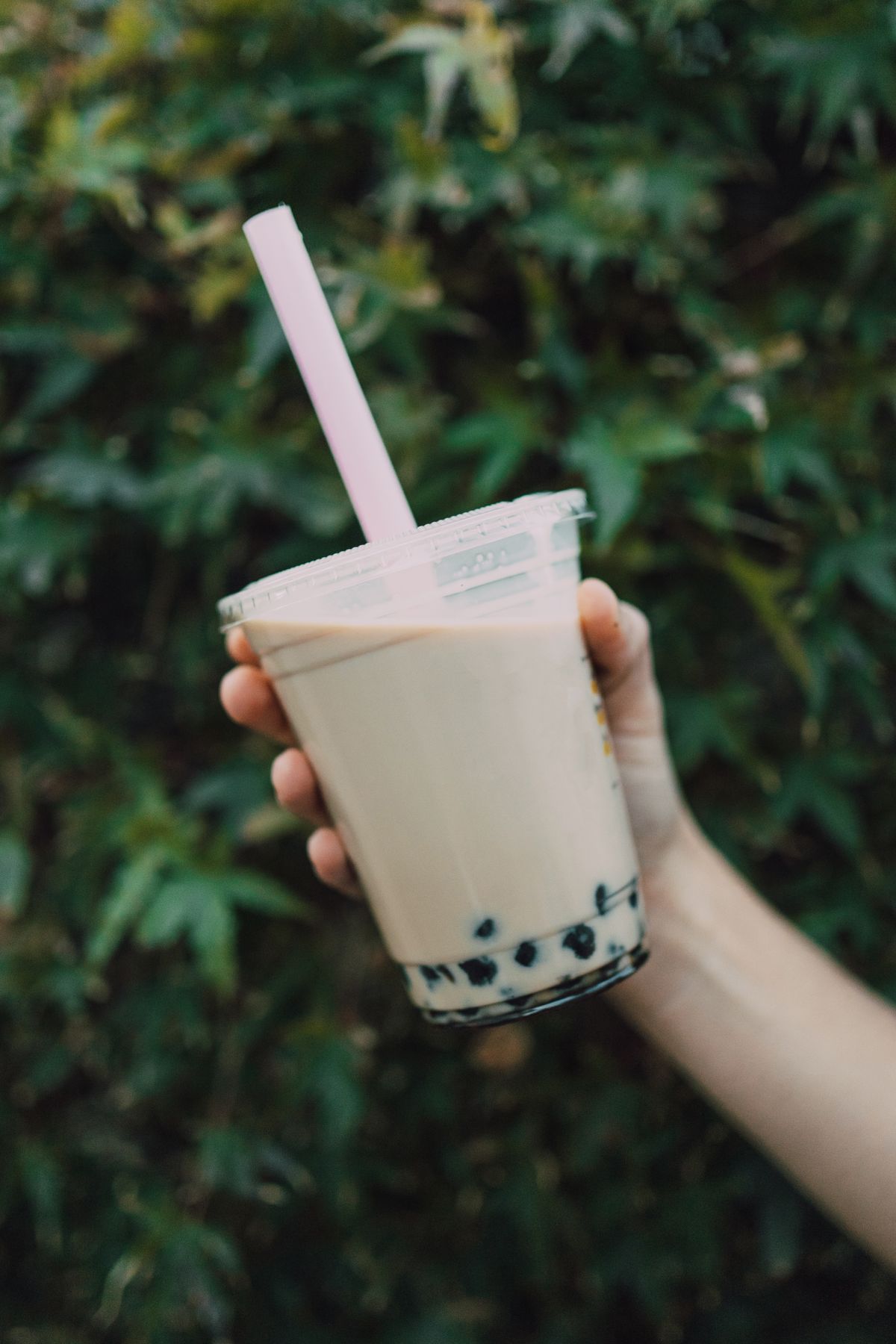 A person holding a cold Asian drink, similar to the grass jelly drinks in Hong Kong's tong sui shops