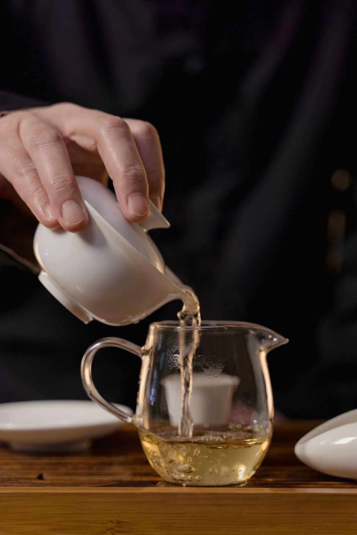 Hands pouring traditional Chinese tea from a ceramic gaiwan